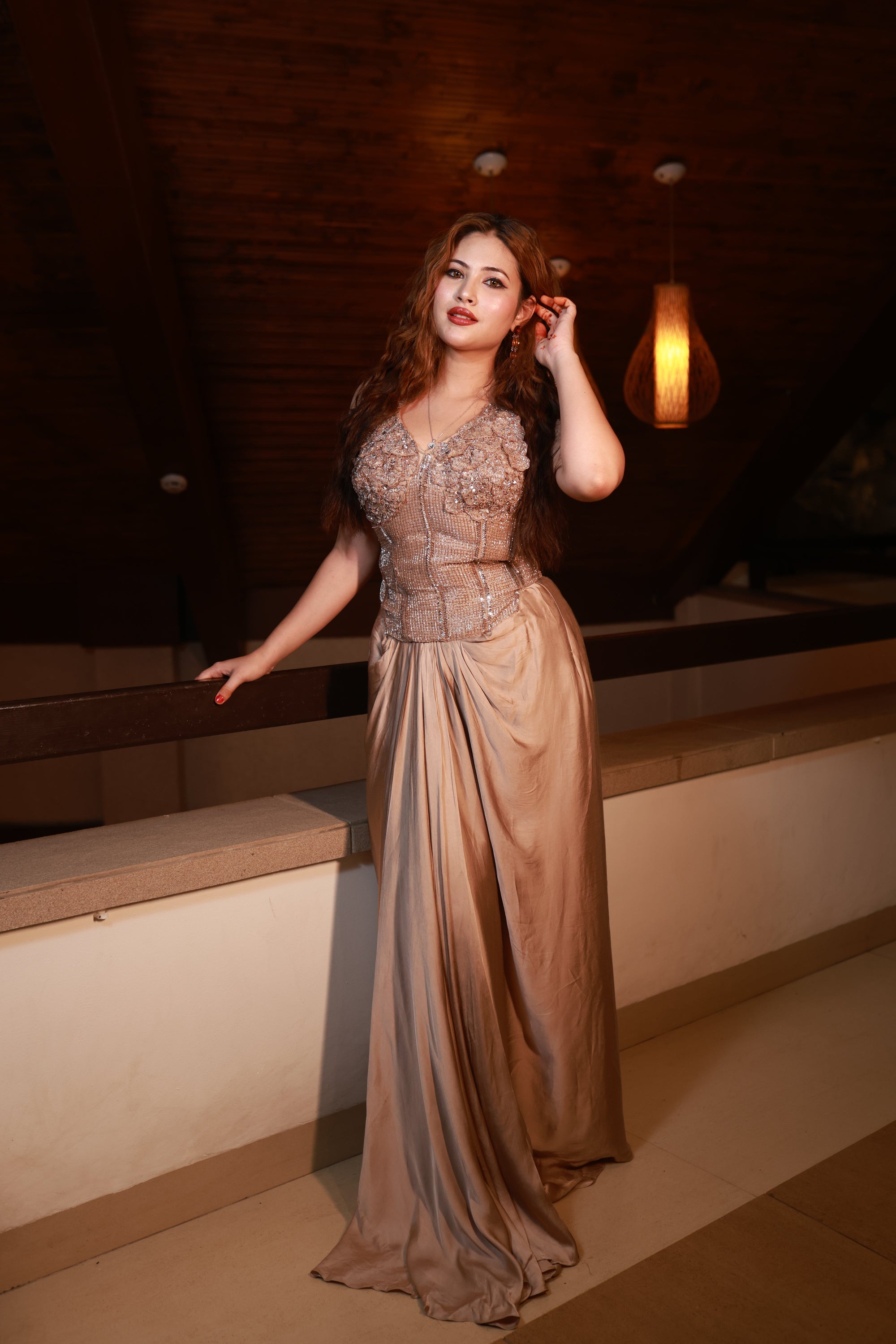 Woman in a long, elegant dress standing in a dimly lit room.